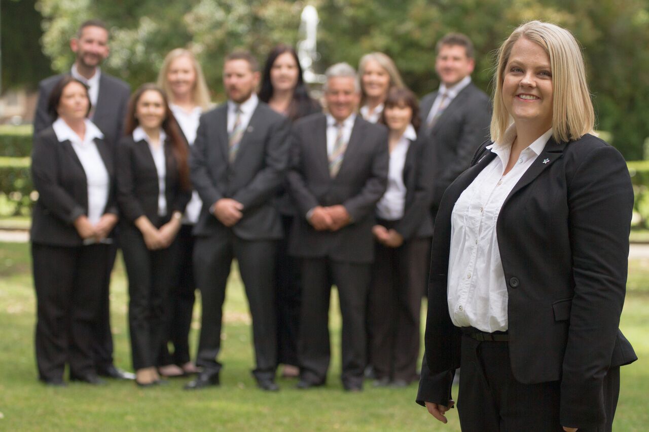 Kristy Saxby standing in front of the Professionals Real Estate Armidale staff