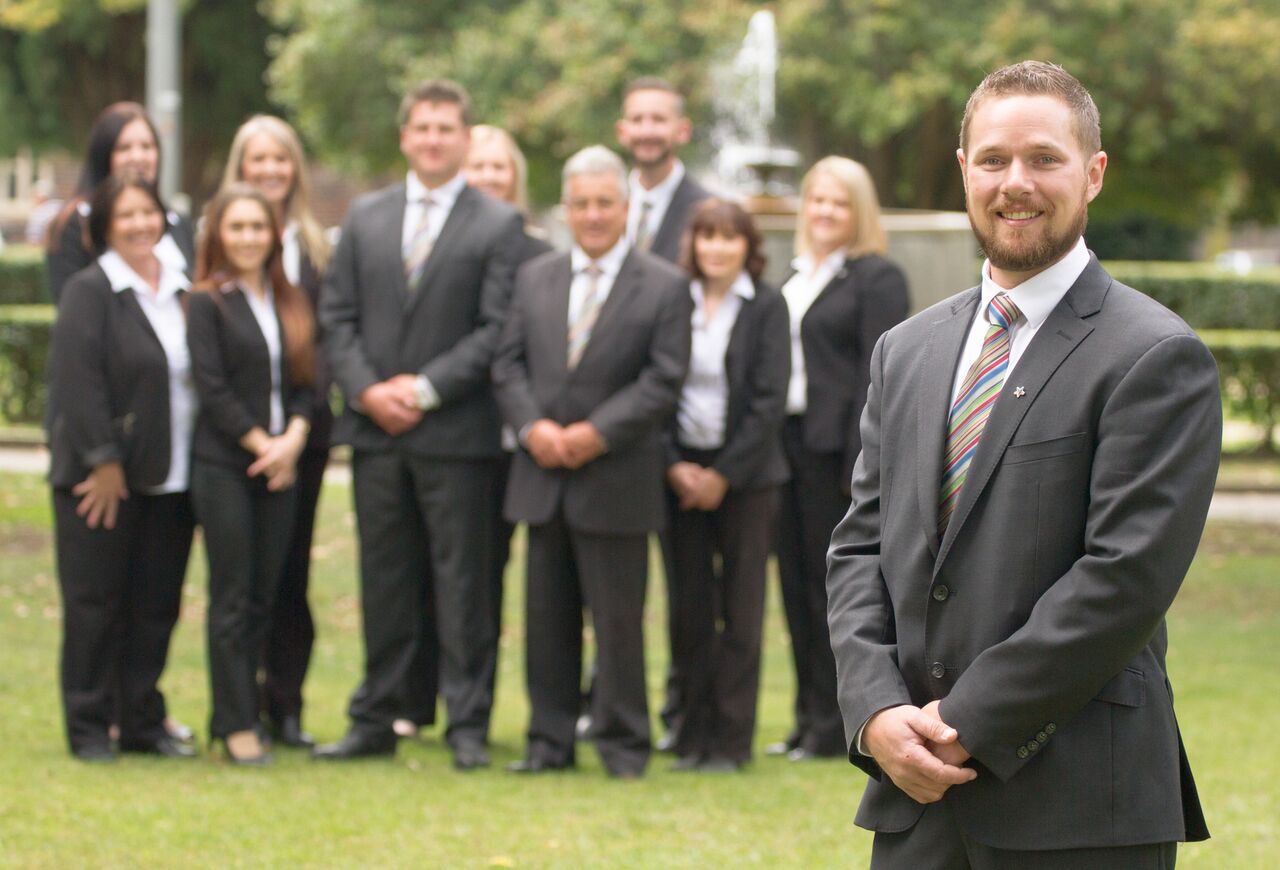 Ben Saxby standing in front of the Professionals Real Estate Armidale staff